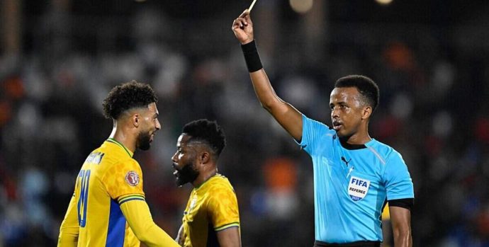 Gabon's forward #20 Denis Bouanga is shown the yellow card by Somali referee Omar Abdulkadir Artan during the Africa Cup of Nations (CAN) Group F football match between Gabon and Ivory Coast at the Grand Stadium in Marrakech on December 31, 2025. (Photo by Khaled DESOUKI / AFP via Getty Images)