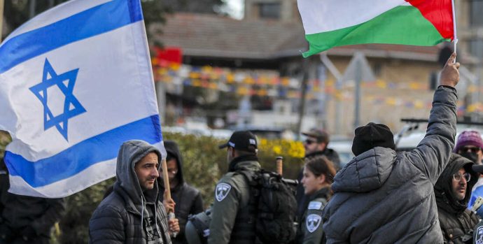 An Israeli settler stands with an Israeli flag before a man holding up a Palestinian flag during a demonstration attended by Palestinians, Israelis, and other foreign activists in the east Jerusalem neighbourhood of Sheikh Jarrah on February 25, 2022, denouncing the evacuation of Palestinian families from their homes and settlement activity in the Palestinian Territories and east Jerusalem. - Israel captured east Jerusalem in the Six-Day War of 1967 and later annexed it, in a move not recognised by the international community. More than 200,000 Jewish settlers have since moved into the city's eastern sector, fuelling tensions with Palestinians, who claim it as the capital of their future state. (Photo by AHMAD GHARABLI / AFP) (Photo by AHMAD GHARABLI/AFP via Getty Images)