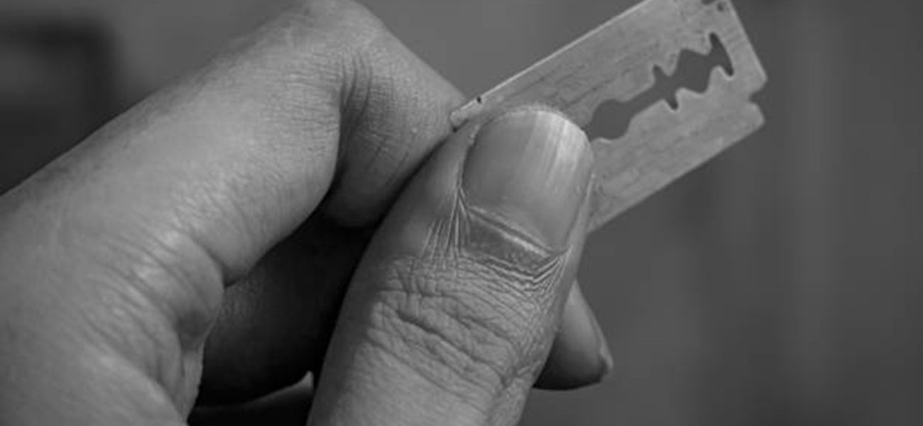 Close up of a hand holding a sharp razor blade