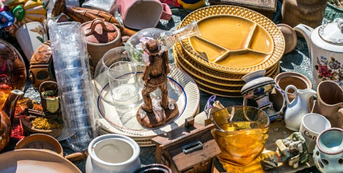 pile of household things, various dishes and decorative objects at boot sale for second hand, recycling or over-consumption society at outdoor welfare